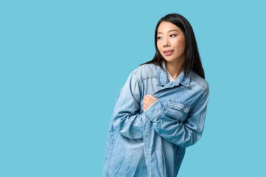Mavi arka planda şık kot elbiseli güzel bir Asyalı kadın.
