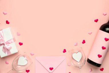 Şarap, gözlük, zarf ve hediye kutusuyla çerçevelenmiş pembe arka planda Sevgililer Günü için