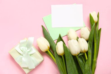 Hediye kutusu olan boş kartlar ve pembe arka planda beyaz laleler.