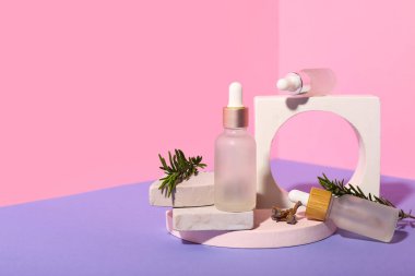 Gerekli yağ şişeleri, taze biberiye ve renk arka planında sıva podyumları ile kompozisyon