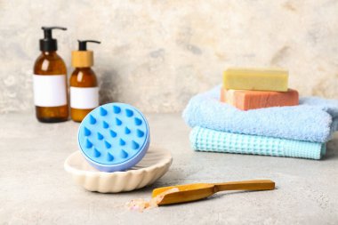 Saç derisi masaj aleti, şampuan barları, kozmetik ürünler şişeleri ve grunge beyaz arka planda havlular.