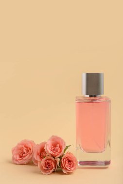 Zarif pembe parfüm şişesi ve bej arka planda güller.