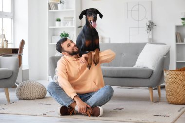 Dobermann 'ın köpeği evde yerde oturan genç adam.