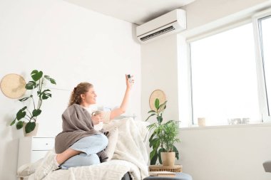Evdeki klimayı açan güzel bir kadın.