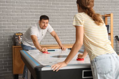 Genç adam ve arkadaşı evde hokey oynuyorlar.