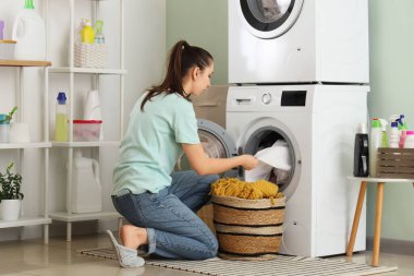 Sepetli genç bir kadın odada çamaşır yıkıyor.