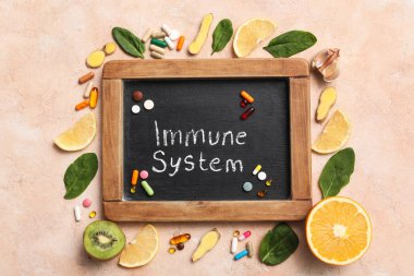 IMMUNE SİSTEM yazılı tebeşir tahtası, arka planda sağlıklı yiyecek ve haplar