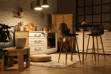 Mutfağın içinde tezgahlar, masa ve gece lambaları var.