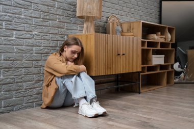 Gri tuğla duvarın yanında oturan yaralı genç bir kadın. Aile içi şiddet kavramı