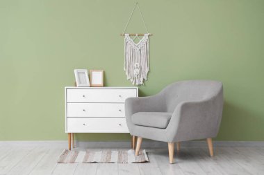 Güzel bir oturma odası, rahat gri koltuğu, çekmeceleri ve makromu var.