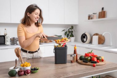 Mutfakta yemek pişirirken gübre kutusu olan genç bir kadın.