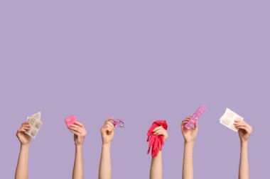 Mor arka planda hardal sıva, eldiven ve ilaç kutuları olan kadın elleri.