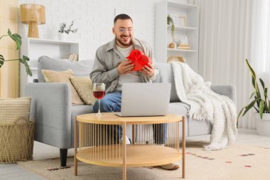 Genç adam evde kız arkadaşıyla sohbet etmek için dizüstü bilgisayar kullanıyor. Online randevu