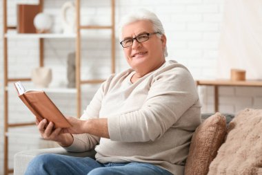 Oturma odasındaki kanepede kitap okuyan yakışıklı bir son sınıf öğrencisiyim.