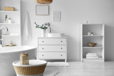 Raflar, göğüs ve çekmeceler. Lavabo, banyonun iç tarafındaki beyaz duvarın yanında.