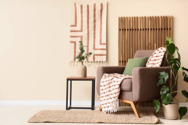 Koltuk, ekose, yastık ve okaliptüs dalları olan bir vazo. Odadaki beyaz duvarın yanındaki sehpanın üzerinde.