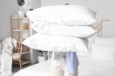 Yatak odasında bir yığın yumuşak yastığı olan genç kadın, yakın plan.