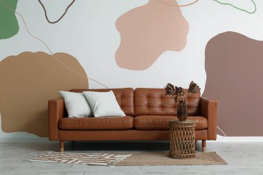 Kahverengi kanepesi ve kurumuş çiçekleri olan şık bir oturma odası.