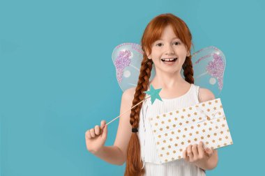 Mavi arka planda sihirli değneği ve hediye kutusu olan sevimli kızıl saçlı peri.