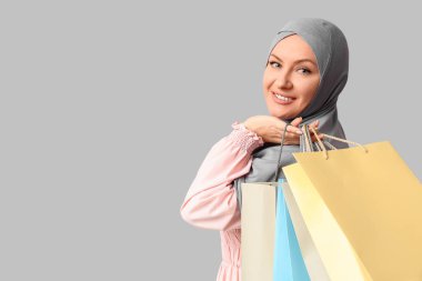 Gri arka planda alışveriş torbaları olan tesettürlü güzel Müslüman kadın