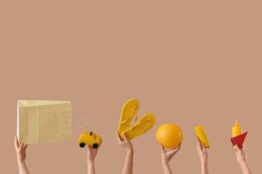 Bej arka planda plaj aksesuarları olan kadın elleri.