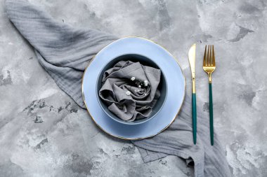 Altın çatal bıçak takımı ve gri arkaplanda çingene çiçekleri olan güzel bir masa.