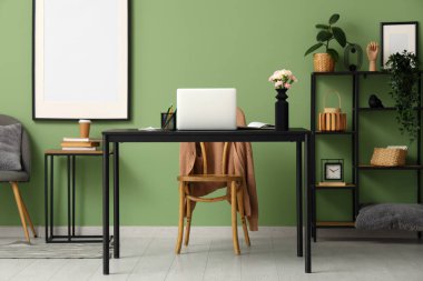 Modern dizüstü bilgisayarı ve güzel çiçekleri olan şık bir çalışma alanı.