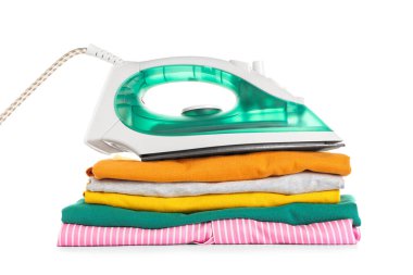 Beyaz arka planda katlanmış temiz giysileri olan modern elektrikli ütü.