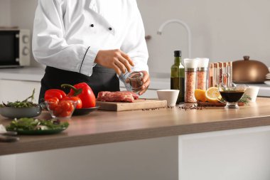 Erkek aşçı mutfakta çiğ et yiyor.