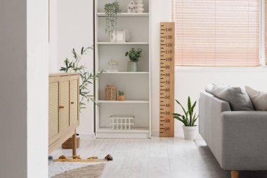 Modern oturma odasının içinde kanepe, raf ünitesi, tuvalet ve pencereye yakın ahşap stadyum var.