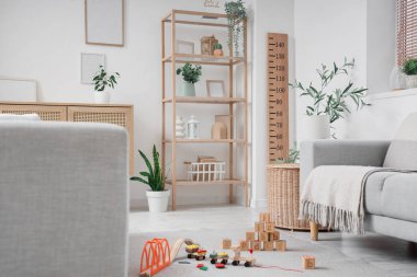 Raflar, ev bitkileri, çocuk oyuncakları ve ahşap stadyumlu modern oturma odasının içi.