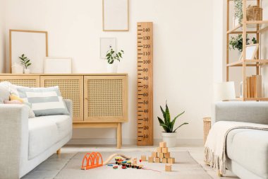 Modern oturma odasının içinde kanepeler, ev bitkileri, çocuk oyuncakları ve ahşap stadyum var.