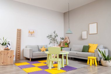 İçinde kanepeler, çocuk masası, ahşap stadyum ve raflarda oyuncaklar olan modern bir oda.