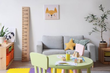 İçinde kanepe, çocuk masası, ahşap stadyum ve raflarda oyuncaklar olan modern bir oda.