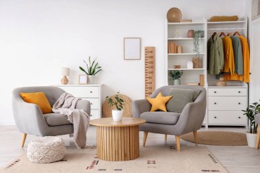 Koltukları, gardırobu, ahşap stadyumu, sehpası ve çiçekleri olan modern oturma odasının içi.