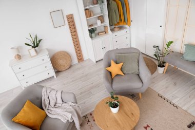 Koltukları, gardırobu, ahşap stadyumu, sehpası ve çiçekleri olan modern oturma odasının içi.