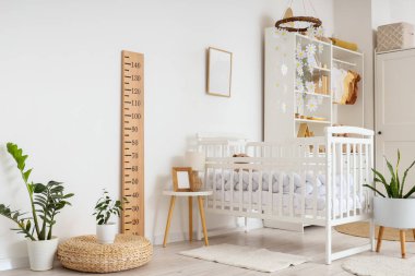 Çağdaş çocukların yatak odasının içinde beşik, gardırop, ev bitkileri ve ahşap stadyum var.