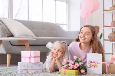 Annesiyle çok tatlı küçük bir kız ve Anneler Günü için oturma odasında hediyeler.