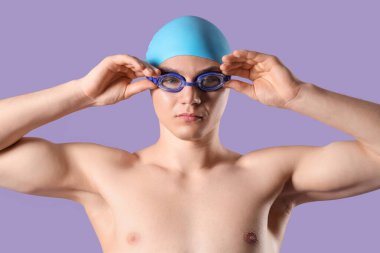 Erkek yüzücü mor arka plana gözlük takıyor