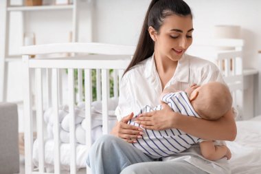Güzel, genç, mutlu bir anne ve tatlı küçük kızı evde yatakta oturuyor.