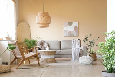 Oturma odasının içinde gri kanepe, koltuk ve rattan masa var.