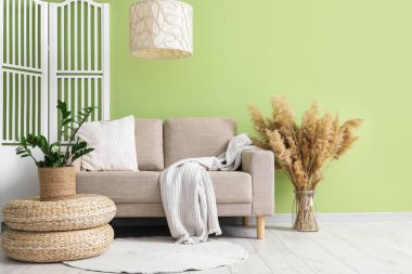 Gri kanepeli, puflu ve katlanır perdeli oturma odasının içinde.