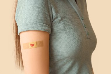 Bej arka planda uygulamalı tıbbi yaması olan genç bir kadın, yakın plan. Dokunulmazlık kavramı