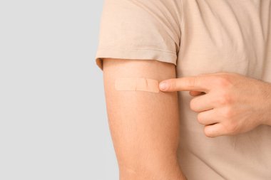 Hafif arka planda uygulamalı tıbbi yaması olan genç bir adam, yakın plan. Dokunulmazlık kavramı