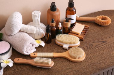 Renk duvarının yanındaki ahşap masada spa aksesuarları ve kozmetik ürünleri.