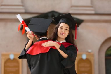 Üniversiteye yakın diplomalı birkaç mutlu mezun öğrenci.