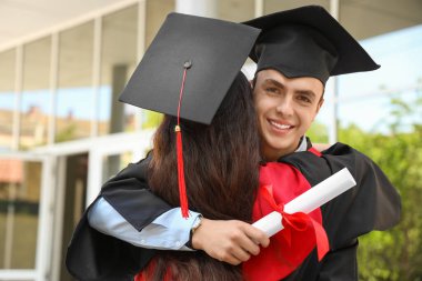 Mezuniyet gününde kucaklaşan diplomalı iki öğrenci.