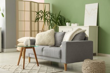 Gri kanepesi, kahve masası ve puf olan şık bir oturma odası.