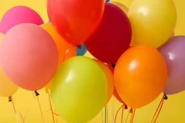 Sarı arka planda renkli hava balonları, yakın plan