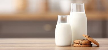 Mutfaktaki ahşap masada tatlı kurabiyeli taze süt şişeleri.